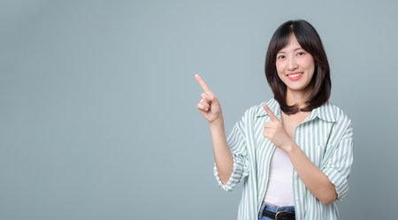 An asian woman smiling and pointing finger, confident female entrepreneur in casual outfit, business success conceptの写真素材
