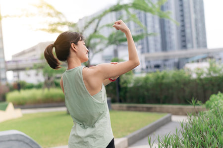 A focused asian woman in an urban city at sunset. fitness yoga workout with stretching exercise reduces shoulder pain muscle strain inflammation and injury risk for medical wellness and healthcareの写真素材