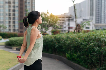 An asian woman fitness yoga workout. stretching exercise reduces shoulder pain muscle strain inflammation injury risk for medical wellness and healthcare in an urban city at sunsetの写真素材