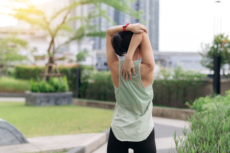 An asian woman an urban city practices fitness yoga workout with stretching exercise. reduces shoulder pain muscle strain inflammation and medical injury risk for wellness and healthcare sunsetの写真素材