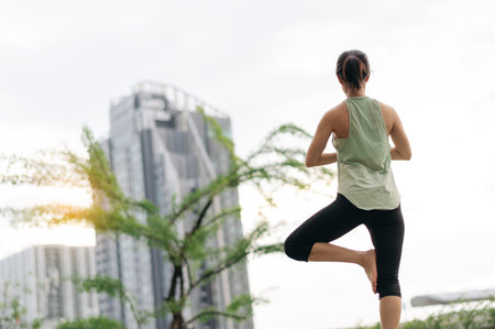 An asian woman fitness yoga workout with stretching exercise at urban city sunset. wellness...