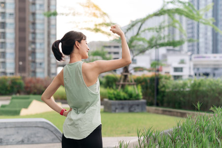 An asian woman fitness workout with stretching yoga exercise reduces shoulder pain muscle strain and inflammation. medical wellness routine for injury risk healthcare in an urban city at sunsetの写真素材