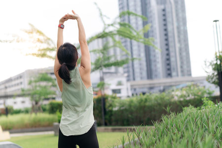 Asian woman 30s fitness yoga workout. Stretching exercise reduces medical injury risk shoulder pain muscle strain inflammation. Healthy lifestyle wellness healthcare an urban city park sunsetの写真素材