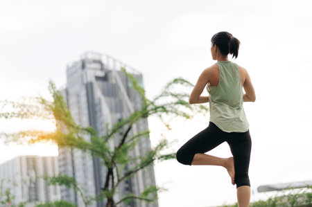 Focused asian woman in 30s fitness yoga workout. An urban city stretching exercise at sunset reduces medical injury risk muscle pain for wellness healthcare and healthy lifestyleの写真素材