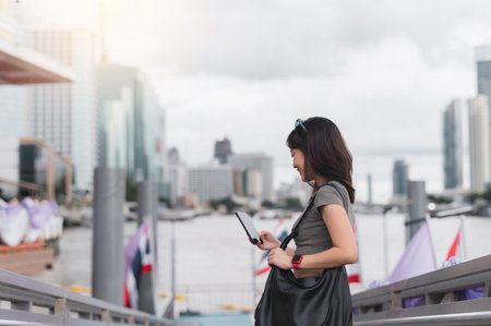 A happy young southeast asian woman teenager and blogger using smartphone searching for travel...