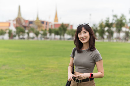 A smiling solo southeast asian woman teenager blogger enjoys world travel tourism. happy explorer with local cultural experience concept in bangkok thailand for trip in asiaの写真素材