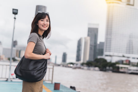 A happy solo southeast asian woman teenager blogger world travel explorer on local cultural tourism experience in thailand wait for express boat on chao phraya river in bangkok asia travel conceptの写真素材