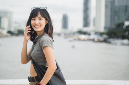 A happy solo southeast asian woman teenager blogger world travel tourism concept. local cultural experience for explorer bangkok thailand. wait for friend express joy by boat chao phraya river asiaの写真素材