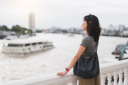 A solo southeast asian woman teenager blogger wait for express boat on chao phraya river bangkok. world travel explorer asia tourism concept local cultural experience in thailandの写真素材