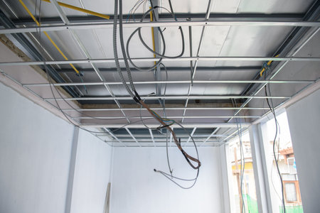 A messy but organized interior renovation project showing electrical wiring installation within an aluminium ceiling framework. room captures feeling of progress and changeの写真素材