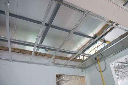 A hopeful interior renovation project showing aluminium ceiling framework and electrical wiring installation. progress visible on structure and system for new roomの写真素材