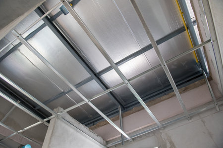 An aluminium ceiling framework during interior renovation shows meticulous electrical wiring installation. grid system supports thermal insulation for modern building updateの写真素材