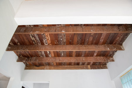 An old rustic wood ceiling brings nostalgic charm to home during renovation. exposed wooden beam and plank create beautiful contrast against white wallの写真素材