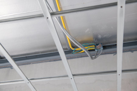 An interior renovation showing electrical wiring and aluminium ceiling framework installation. meticulous construction highlights grid and junction box for new buildingの写真素材