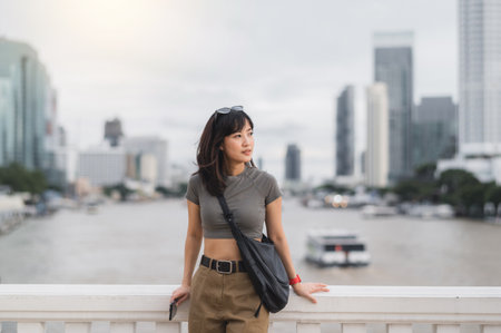 A solo southeast asian woman teenager blogger world travel explorer on local cultural experience to wait for an express boat on chao phraya river in bangkok thailand. asia tourism conceptの写真素材