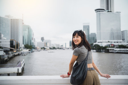 A happy solo southeast asian woman teenager blogger, world travel explorer. wait for express boat on chao phraya river in bangkok, local cultural tourism experience concept in thailand, asiaの写真素材