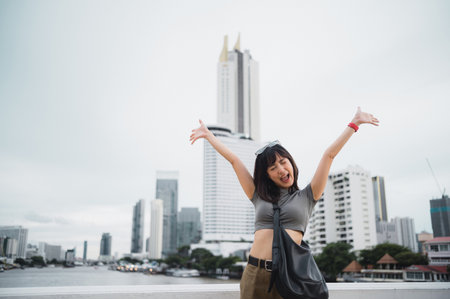 A happy solo young southeast asian woman teenager blogger world travel explorer with smartphone. local cultural tourism experience concept by chao phraya river in bangkok asia thailandの写真素材
