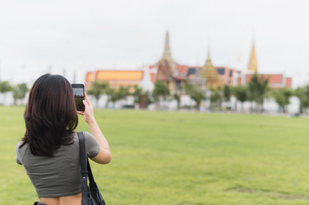 Happy southeast asian woman teenager blogger on solo world travel tourism in Bangkok Thailand take photo with smartphone. An asia local cultural experience for an explorer conceptの写真素材