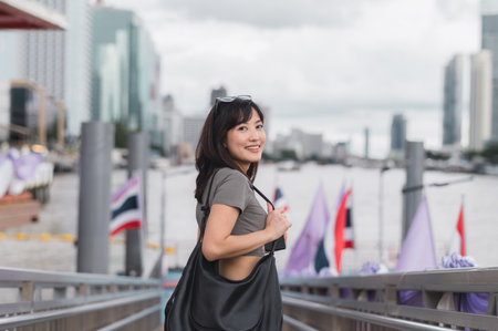 Young southeast asian woman teenager blogger using smartphone searching tourism guide. world travel explorer concept for local cultural experience in Bangkok Asia by Chao Phraya riverの写真素材