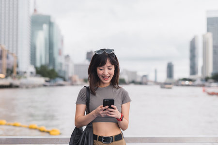 Young southeast asian woman teenager blogger searching map smartphone for guide near chao phraya river bangkok thailand. world travel explorer concept for local cultural experience asia tourismの写真素材