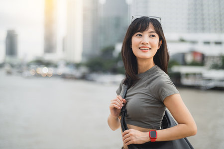 Happy young southeast asian woman solo travel blogger enjoying tourism in Bangkok Thailand. local cultural experience for teenager explorer by Chao Phraya River in Asiaの写真素材
