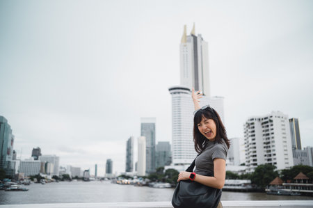 Solo world travel explorer. Happy young southeast asian woman and teenager blogger with smartphone. Asia tourism concept for local cultural experience on Chao Phraya river in Bangkok Thailandの写真素材