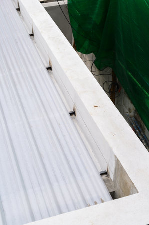 Close up view shows white corrugated sheet secured to metal frame detail from construction site utilizing foam insulation potentially with pu properties suggesting protection from elementsの写真素材