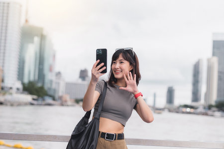 Happy solo southeast asian woman teenager blogger on world travel tourism in Bangkok Thailand express joy local cultural experience an explorer uses smartphone by boat on Chao Phraya river Asiaの写真素材