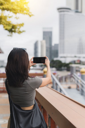 Solo southeast asian woman teenager blogger world travel tourism. Explorer takes photo of Bangkok city Chao Phraya River with smartphone from boat. happy local cultural experience Thailand, Asiaの写真素材