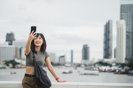 Selfie with smartphone from beautiful young southeast asian woman 30s teenager blogger. World travel explorer Chao Phraya river Bangkok. Asia summer tourism concept for local cultural experienceの写真素材