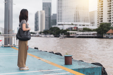 Solo southeast asian woman teenager blogger and world travel explorer get local cultural experience. Wait for an express boat on Chao Phraya river in Bangkok Thailand. Asia tourism conceptの写真素材