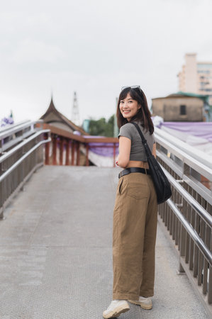 Happy solo Southeast Asian woman teenager blogger and world travel explorer. local cultural tourism experience in Bangkok Thailand to wait for Chao Phraya River express boat. Asia travel conceptの写真素材