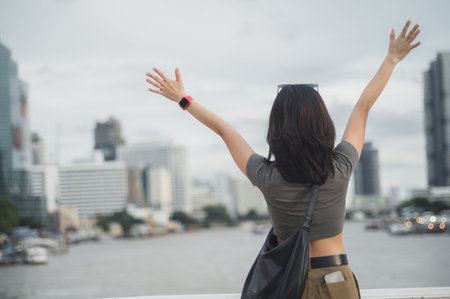 Happy solo young southeast asian woman teenager blogger on world travel. Explorer local cultural experience. Asia tourism concept in Bangkok Thailand by Chao Phraya River with smartphoneの写真素材