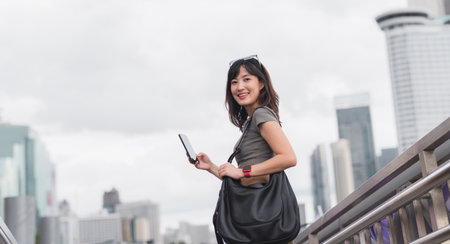 Happy young southeast asian woman teenager blogger using smartphone for searching travel guide. World explorer with local cultural experience on Chao Phraya river in Bangkok Asia tourism conceptの写真素材