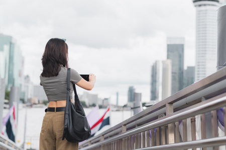 Solo southeast asian woman teenager blogger world travel explorer wait to take photo with smartphone. Local cultural experience and asia tourism concept express boat Chao Phraya River Bangkokの写真素材