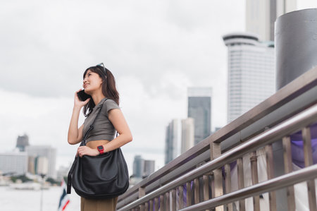 Solo southeast asian woman teenager blogger world travel tourism express joy smartphone wait for friend boat Chao Phraya river Bangkok local cultural experience travel explorer asia conceptの写真素材
