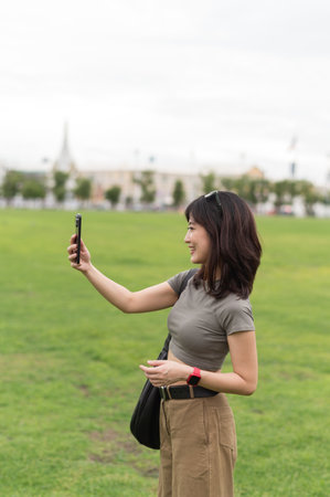 Happy southeast asian woman teenager blogger on solo travel take smartphone photo. world explorer enjoying local cultural experience for tourism concept in Bangkok, Thailand, Asiaの写真素材