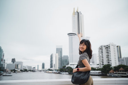 Happy solo young southeast asian woman teenager blogger explorer on world travel. Asia tourism concept for local cultural experience with smartphone by Chao Phraya River in Bangkok Thailandの写真素材