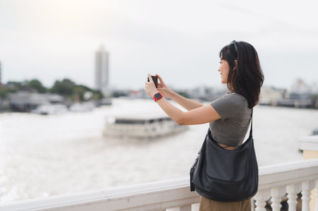 Solo southeast asian woman teenager blogger world travel explorer wait take photo with smartphone express local cultural experience on boat Chao Phraya River Bangkok Thailand asia tourism conceptの写真素材
