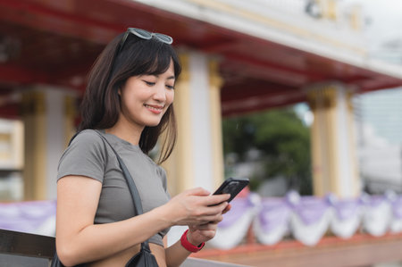Happy young southeast asian woman teenager blogger searching travel map guide on smartphone for local cultural tourism experience in Bangkok Thailand for world travel in Asiaの写真素材