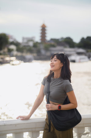 Happy solo young southeast asian woman teenager blogger with smartphone, world travel explorer in asia. Tourism concept for local cultural experience at Chao Phraya River Bangkok Thailandの写真素材