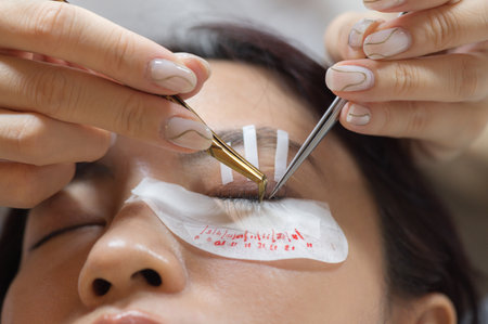 Young southeast asian woman in beauty salon undergoes calm eyelashes extension procedure....