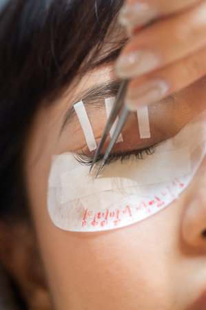 Young southeast asian woman getting eyelashes extension procedure in beauty salon. Female enhancing...