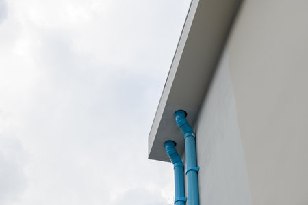 Architectural detail of blue drainage pipe system on house wall. functional part of construction or...