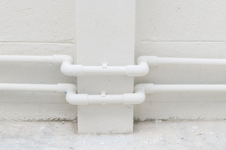 Minimalist construction detail on house exterior during renovation project. White pipes on white...