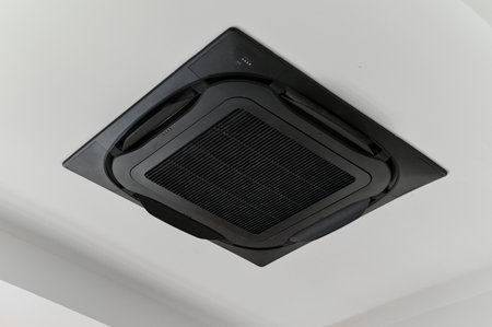 Black ceiling air conditioner for climate control system. Modern ventilation equipment providing cool and comfortable atmosphere in room. HVAC technology for home interiorの写真素材