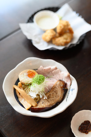 Delicious bowl of authentic japanese ramen with pork and soft boiled egg at cozy restaurant. warm and comforting meal enjoyed with tasty side dish for lunchの写真素材