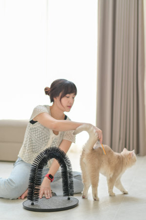 Relaxed asian woman gently petting friendly domestic cat at home promoting mental health wellness and positive emotional animal care bonding with furry feline pet sitting on floorの写真素材