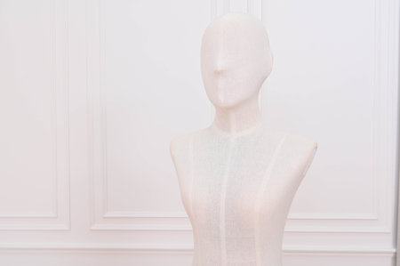 Anonymous white mannequin bust in minimal fashion boutique. elegant, faceless dummy form stands in clean studio room with classic molding for display or retailの写真素材