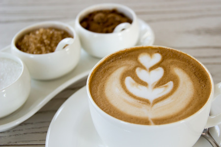 Latte art with different kinds of sugar on wooden tableの写真素材